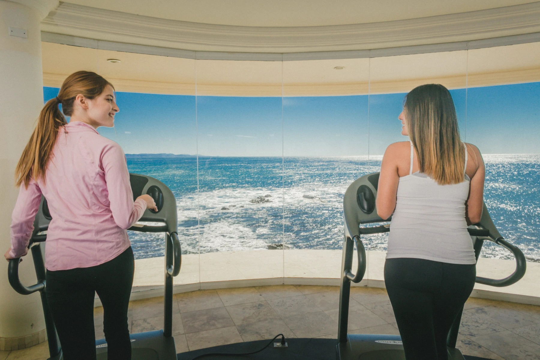 One-to-One Conversation in the Oceanfront Room Two people in a one-to-one conversation in the curved oceanfront room at Holistic Sanctuary, with the Pacific filling the windows behind them
